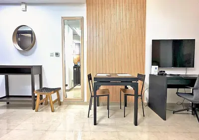 a living room with a table and a piano at Lovely Studio Apartment in Hanover Square, JVC in Dubai