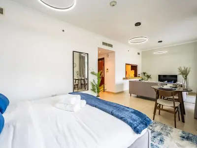 a bedroom with a large white bed and a living room at Incredible Studio In Burj View in Dubai