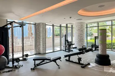 a gym with several treadmills and machines in a room with windows at HiGuests - Emaar Beachfront Haven with Majestic Marina Views in Dubai