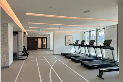 a gym with a row of treadmills and machines at HiGuests - Emaar Beachfront Haven with Majestic Marina Views in Dubai