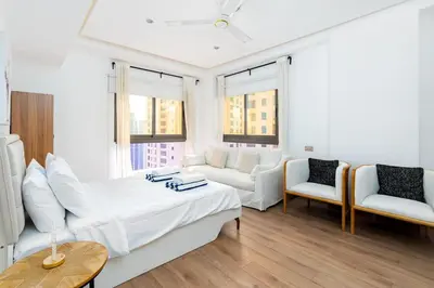 a white room with a bed and a couch and chairs at JBR Bahar Beach Views 4 beds - DVH Holiday Homes in Dubai
