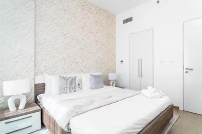 a white bedroom with a bed and a white wall at Nasma Luxury Stays - Home-Style 2BR Apartment with a Balcony View in Dubai