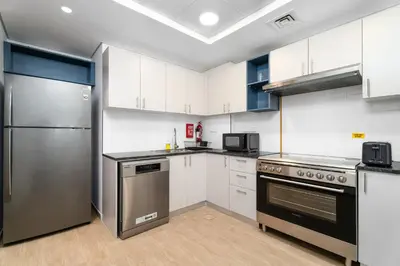 a kitchen with white cabinets and a stainless steel refrigerator at Nasma Luxury Stays - Home-Style 2BR Apartment with a Balcony View in Dubai