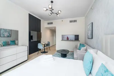 a bedroom with a white bed and a living room at Nasma Luxury Stays - Sophisticated Studio Apt with Stunning Marina View in Dubai