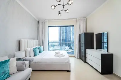 a bedroom with a bed and a tv and a couch at Nasma Luxury Stays - Sophisticated Studio Apt with Stunning Marina View in Dubai