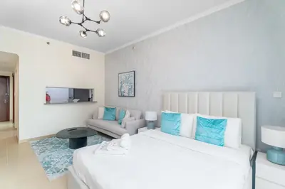 a bedroom with a large white bed and a couch at Nasma Luxury Stays - Sophisticated Studio Apt with Stunning Marina View in Dubai