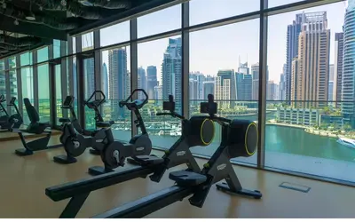 a gym with cardio machines in front of a large window at Dubai Marina Gate 2 Deluxe Apartment in Dubai