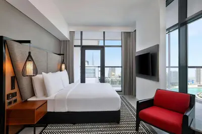 a hotel room with a bed and a red chair at The First Collection Waterfront, Dubai, a Tribute Portfolio Hotel in Dubai