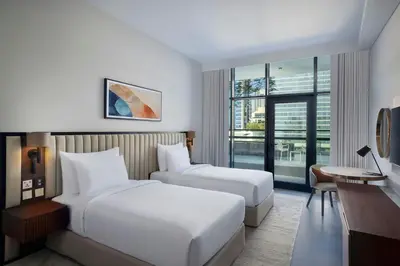 a hotel room with two beds and a desk at The First Collection Waterfront, Dubai, a Tribute Portfolio Hotel in Dubai