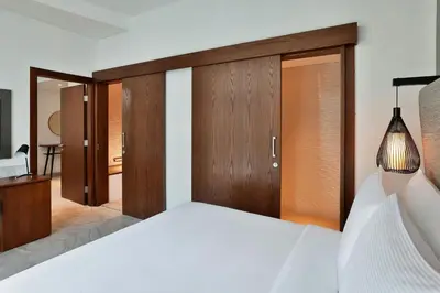 a bedroom with a white bed and wooden doors at The First Collection Waterfront, Dubai, a Tribute Portfolio Hotel in Dubai