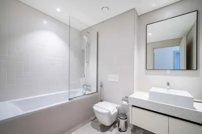 a bathroom with a sink and a toilet and a mirror at Marina Vista 1 Bed with Private Beach and Gorgeous Skyline in Dubai