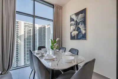 a dining room with a table and chairs and a large window at Citihome - 1BR at Merano Tower by Damac in Dubai