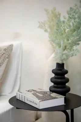 two books on a table next to a vase at Modern studio in Azizi Riviera in Dubai