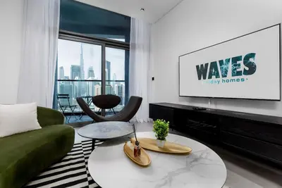 a living room with a green couch and a tv at Waves Holiday Homes - 15 Northside, Tower 1, Two Bedroom in Dubai