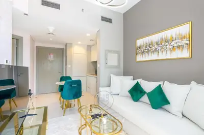 a living room with a white couch and green chairs at 1BR Zada Tower l Two Balconies & City Views in Dubai