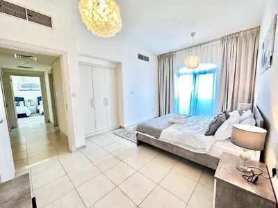 a bedroom with a large bed and a chandelier at Golf Facing 5Bedroom Villa in Novelia Village in Dubai