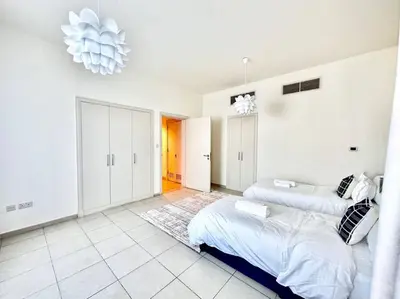 a white bedroom with two beds and a chandelier at Golf Facing 5Bedroom Villa in Novelia Village in Dubai