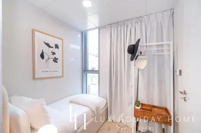 a white room with a bed and a window at LUX The District One Lagoon View Suite in Dubai