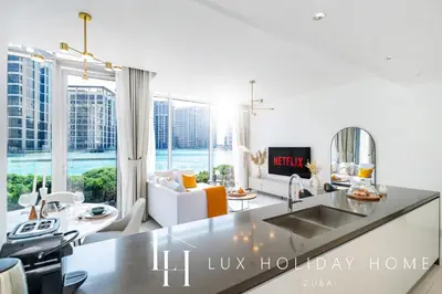 a kitchen and living room with a view of the ocean at LUX The District One Lagoon View Suite in Dubai