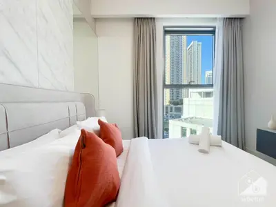 a white bed with orange pillows and a window at Luxurious stay Dubai Creek Balcony & View in Dubai