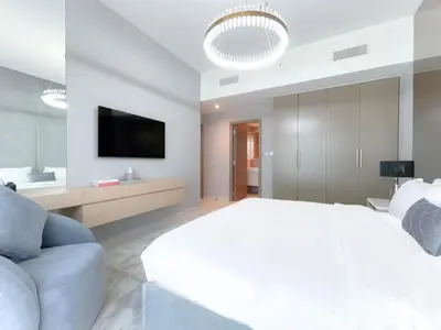a white bedroom with a large bed and a tv at Luxury Burj Royale Burj Khalifa & Fountain view in Dubai
