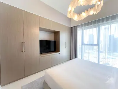 a bedroom with a bed and a tv and a chandelier at Luxury Burj Royale Burj Khalifa & Fountain view in Dubai