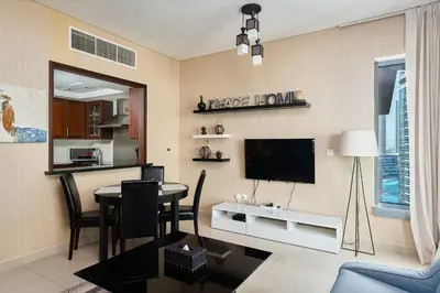 a living room with a table and a tv on the wall at Bellavista - 1 BR - with Extra Room - Partial Fountain View in Dubai