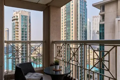 a balcony with a table and chairs and tall buildings at Bellavista - 1 BR - with Extra Room - Partial Fountain View in Dubai