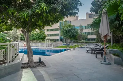 a pool with chairs and an umbrella next to a building at Bellavista - 1 BR - with Extra Room - Partial Fountain View in Dubai