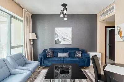 a living room with a blue couch and a table at Bellavista - 1 BR - with Extra Room - Partial Fountain View in Dubai