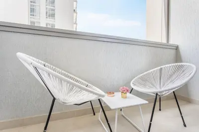 two white chairs and a table in front of a wall at STAY BY LATINEM Luxury 2BR Holiday Home CV A814 near Burj Khalifa in Dubai