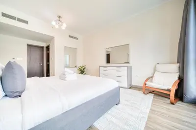 a white bedroom with a large bed and a chair at Burj Residence 1, Downtown Dubai - Mint Stay in Dubai