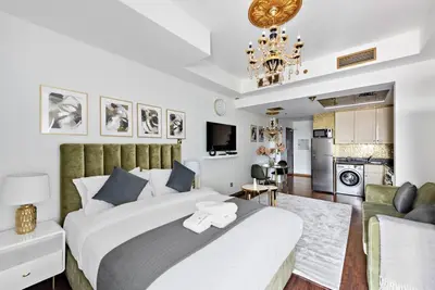 a bedroom with a large white bed and a kitchen at StoneTree - Elegant Studio in Goldcrest View in Dubai