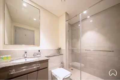 a bathroom with a shower and a sink and a mirror at Oraya - Modern Apt 5 min walk to Dubai Mall & Burj Views in Dubai