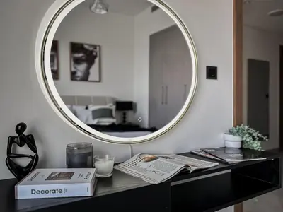 a mirror sitting on top of a black table with a book at Trophy - Cozy Elegant Suites in Dubai