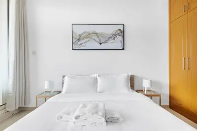 a bedroom with a white bed with towels on it at StoneTree - Furnished 1BR with Spacious Balcony in Dubai