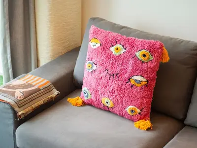 a pink pillow with eyes on a couch at Cozy 1 BR in Dubai Marina in Dubai