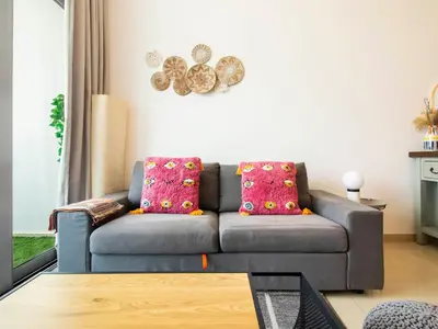 a living room with a gray couch with pink pillows at Cozy 1 BR in Dubai Marina in Dubai