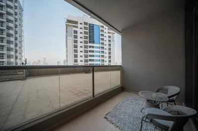 a balcony with chairs and a table and a large window at Studio in Dubai