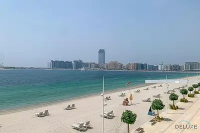 a beach with chaise lounges and chairs and the ocean at Inviting 1BR at Beach Vista Tower 1 Emaar Beachfront Dubai Marina by Deluxe Holiday Homes in Dubai