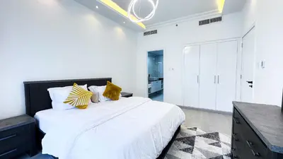 a white bedroom with a large bed with yellow pillows at Jumeriah Lake Tower(JLT)- (MAG214)(2) in Dubai