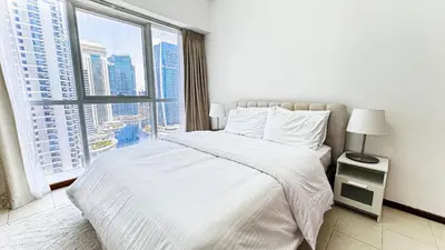 a bedroom with a white bed and a large window at Jumeriah Lake Tower (JLT)-(MAG214)(1) in Dubai