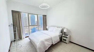 a white bedroom with a bed and a large window at Jumeriah Lake Tower (JLT)-(MAG214)(1) in Dubai