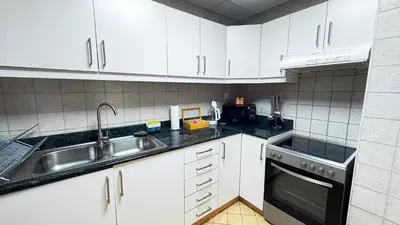 a kitchen with white cabinets and a sink at Jumeriah Lake Tower (JLT)-(MAG214)(1) in Dubai