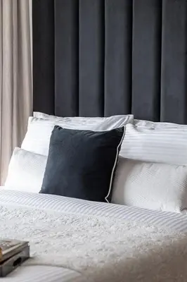 a bed with a black pillow and white pillows at Frank Porter - Reva Residences in Dubai