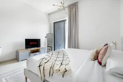 a white living room with a white couch and a tv at GuestReady - Mesmerizing views of the Burj Khalifa in Dubai