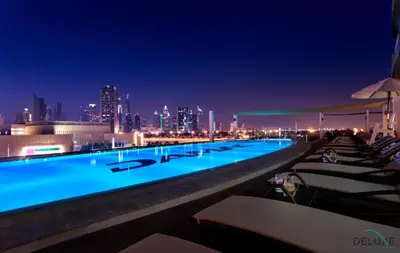 a swimming pool with a city skyline at night at Chic 1BR at The Signature Downtown Dubai by Deluxe Holiday Homes in Dubai