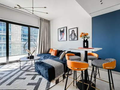 a living room with a blue couch and orange chairs at Trophy - Luxury Canal View Suites. in Dubai