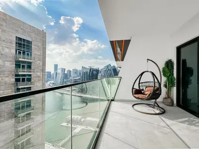 a chair on a balcony with a view of the city at Trophy - Luxury Canal View Suites. in Dubai