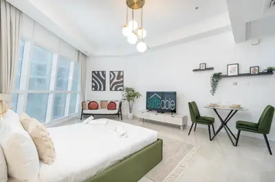 a white bedroom with a bed and a table and chairs at Comfortable Broad Studio in Business Bay-Suiteable in Dubai